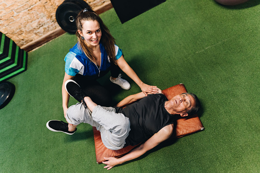 Portrait of a teacher helping student during stretching class at the gym