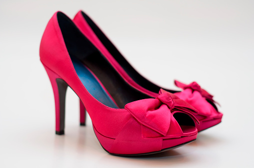 A front view of two pink high heel pumps with bows. Shallow DOF.