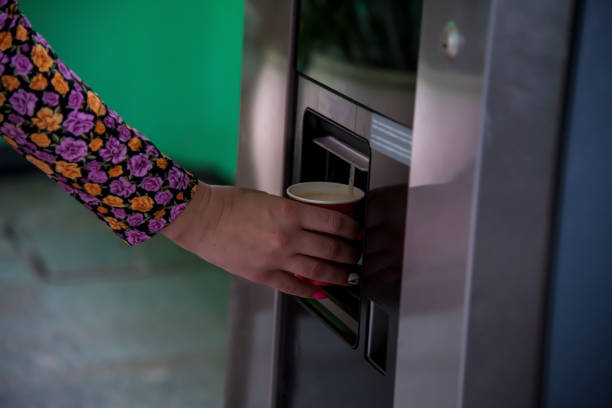 istock Woman picking up coffee cup from vending machine 1601445007