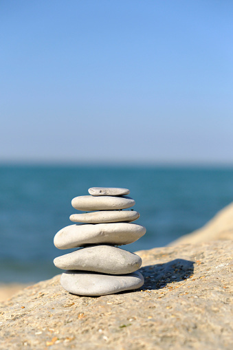 Pebble tower balance harmony stones arrangment on sea beach coastline. Spa therapy summer travel vacation.
