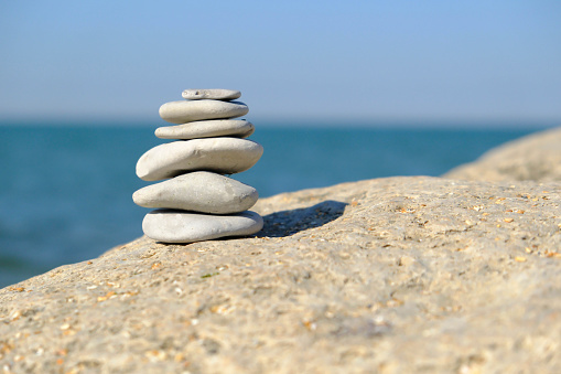 Pebble tower balance harmony stones arrangment on sea beach coastline. Spa therapy summer travel vacation.