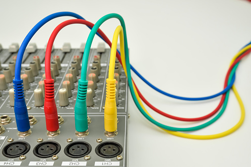 Audio jack plugs on music mixing console for connecting music devices. Different colors audio cables for connecting and recording music instrument.