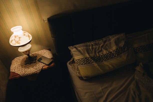 Bedside lamp turns on in bedroom at dusk.