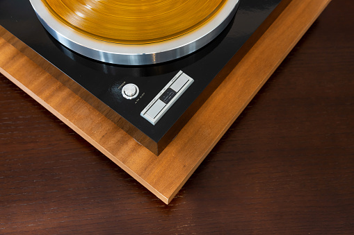 Close-up of an old vinyl record sitting on a dusty portable turntable