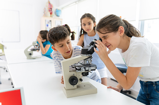 elementary students using microscope in laboratory