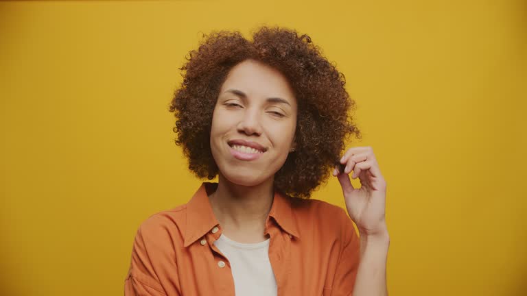 Shy Curly Woman Posing on Camera on Yellow Background