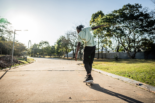 teenage asian child skateboarding outdoors on a pedestrian bridge