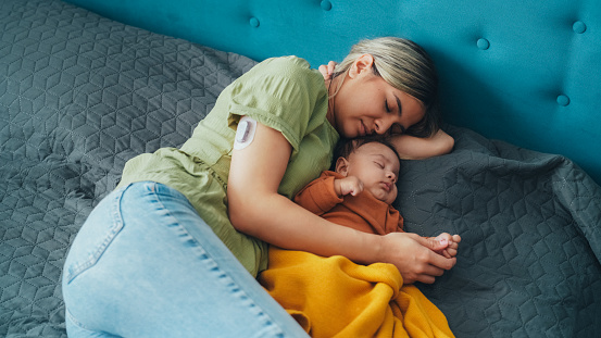 Young mother with diabetes sleeping with her baby boy in bed