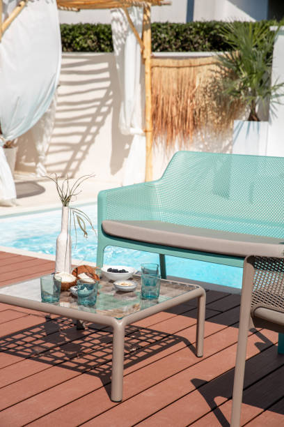 istock Outdoor garden living space pool area with sofa couch, table and refreshment drinks on terrace patio 1601537060