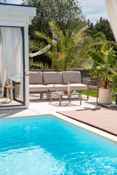 istock Outdoor garden living space pool area with sofa couch, table and refreshment drinks on terrace patio 1601537424