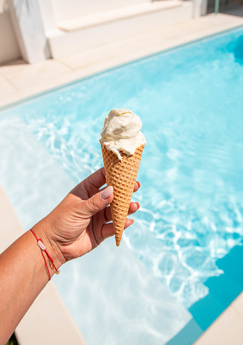 Hand holding ice cream cone at swimming pool