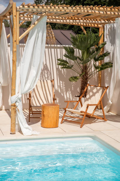 istock Boho Sun chairs under driftwood pergola by the swimming pool in warm sunlight 1601540271