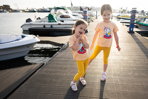 Two little girls playing on a pier in the port of Nessebar, Bulgaria.