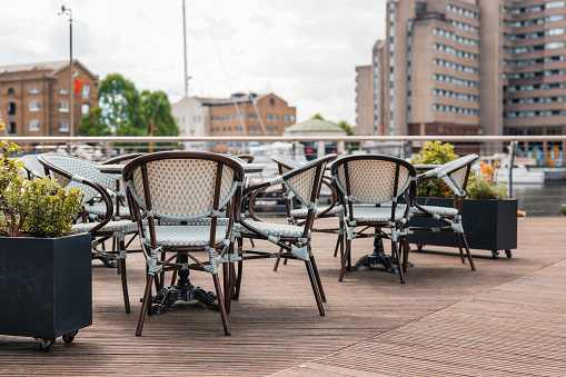 Empty outdoor restaurant tables and chairs in St Katherine's Dock in London, UK, selective focus.