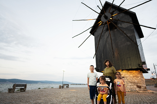 Mother with children standing in front of a windmill on the beach Nessebar.