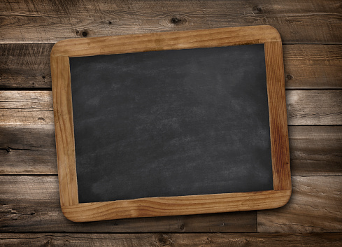 Antique miniature portable black chalkboard with wood frame and smudged chalk on rustic wooden background