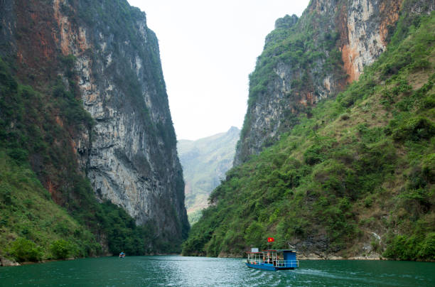 The scenic view of a deep canyon and tourist bouts traveling along Nho Que River (Vietnam).