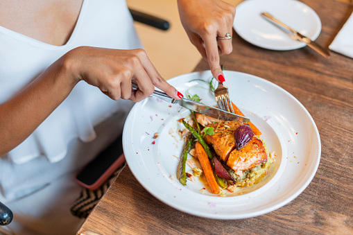 Latina woman of average age, 25 years old, with blonde hair, is in the restaurant of a hotel where she is staying, enjoying a delicious dinner