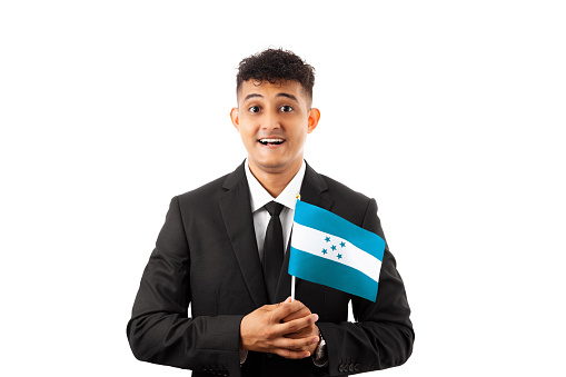 Young hispanic man business suit holding honduras flag looking positive and happy standing and smiling with a confident smile showing teeth