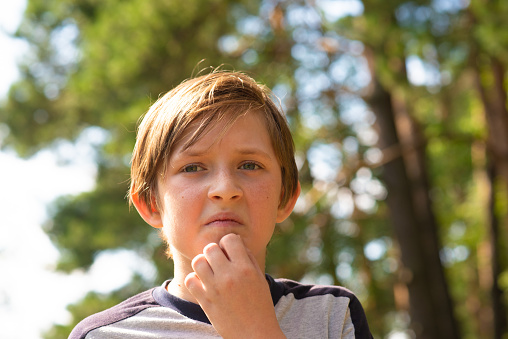 portrait of pensive boy outside. 10 year old emotional, upset child in nature.