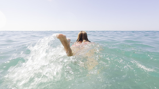 mature adult woman splashing her feet and swimming in the sea water