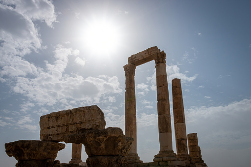 Ruins of Roman Hercules Temple with its cloumns on Citadel Hill in Amman, Jordan against blue sky with clouds