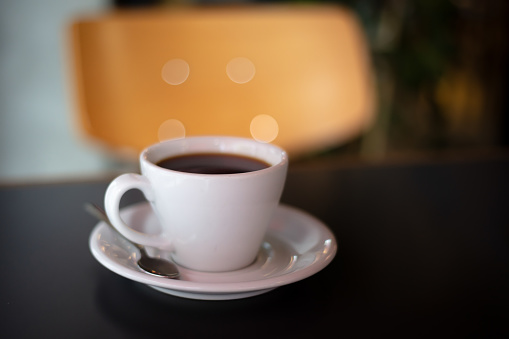 Fresh filter coffee in white mug standing on cafe table.