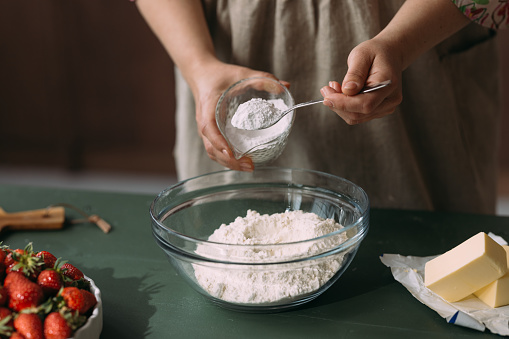 A close up view of an unrecognizable Caucasian female making a cake.