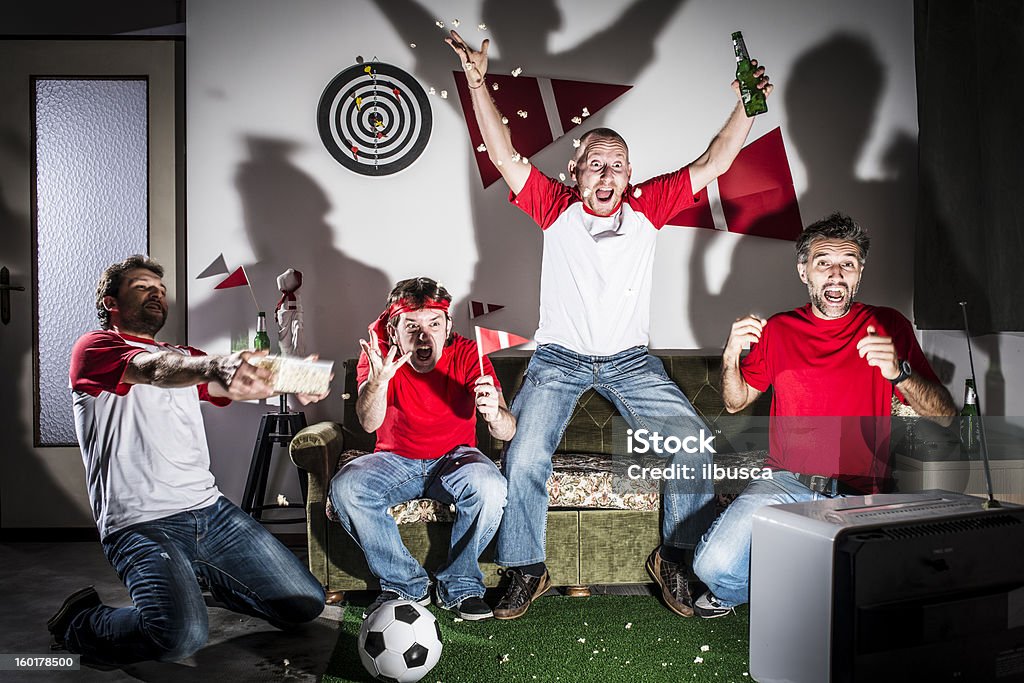 Cuatro adultos, hombres jóvenes amigos viendo el fútbol en televisión: Objetivo. - Foto de stock de Fútbol libre de derechos