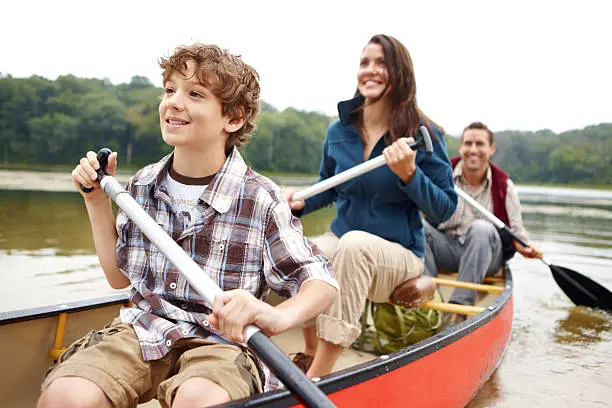 A young boy enjoying a kayak ride out on the lake with his parents