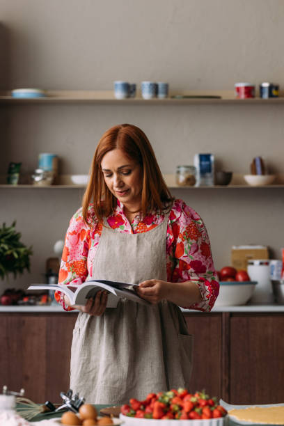 istock A Happy Beautiful Ginger Woman With An Apron Reading A Book About Cooking While Making A Dessert 1601787419