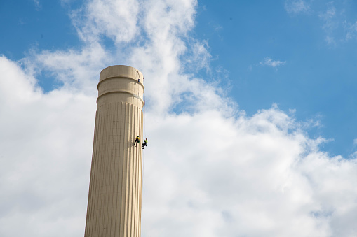 London, United Kingdom - August 30, 2022: Workers climbing a chimney on Battersea Power Station