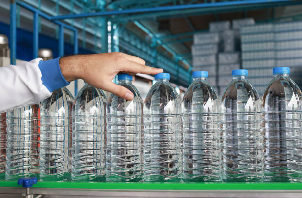 Drinking  Water bottles on the conveyor belt in process manufacturing.  The quality control inspector picked up a bottle from the running conveyer belt.