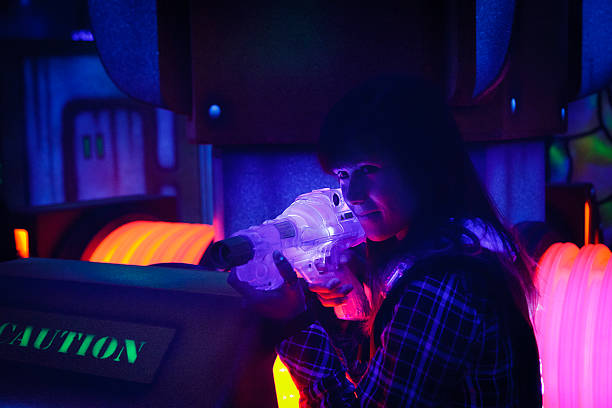 Laser Tag A teen girl playing laser tag.  Photographed at a high ISO under blacklight to capture true look and feel of game. playing tag stock pictures, royalty-free photos & images