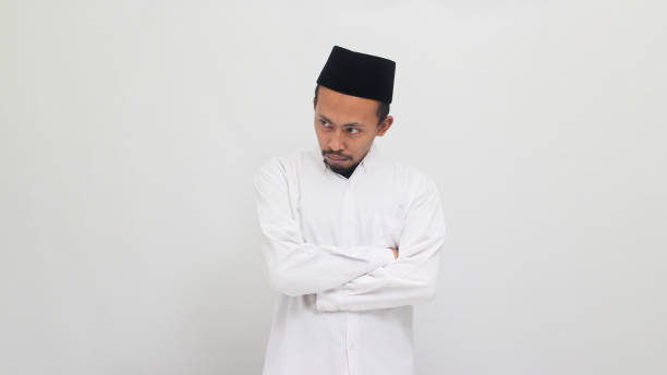 istock Angry young Indonesian man keeps his arms folded, feeling annoyed, isolated on white background 1601880037