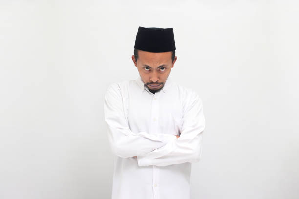 istock Angry young Indonesian man keeps his arms folded, looking at camera, isolated on white background 1601881513