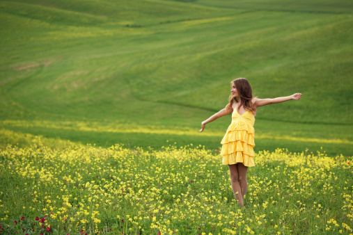 Free happy young woman in a field enjoying nature