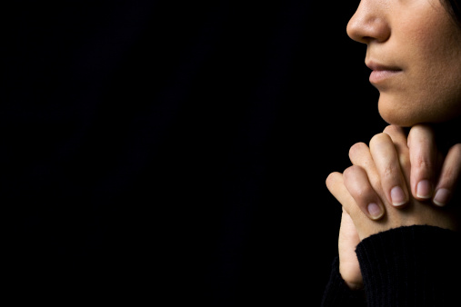 Religious adult believing in Jesus and praying in studio, showing belief and being hopeful over black background. Spiritual man feeling optimistic and talking to God. Handheld shot. Close up.