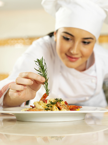 Female chef completing pasta.