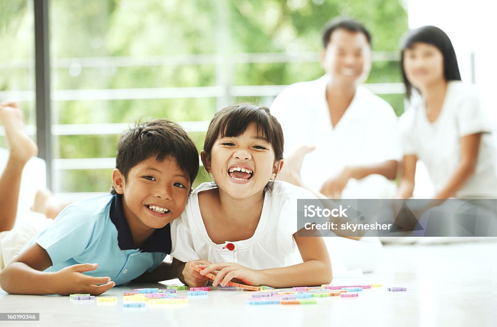 Alegre niños jugando con un rompecabezas en su hogar. - Foto de stock de Acostado libre de derechos