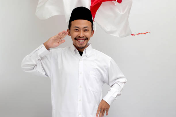 istock Excited young Indonesian man is making a salute gesture with Indonesia flag in the background 1601905607