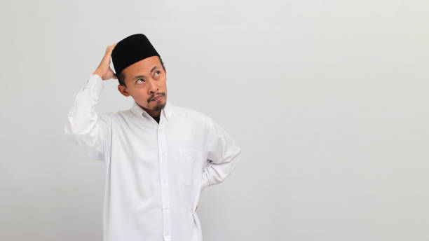 istock Pensive young Indonesian man is scratching his head, deep in thought, isolated on white background 1601918192