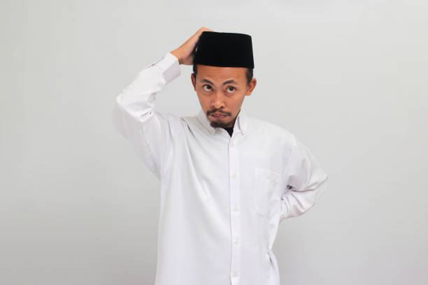 istock Pensive young Indonesian man is scratching his head, deep in thought, isolated on white background 1601919222