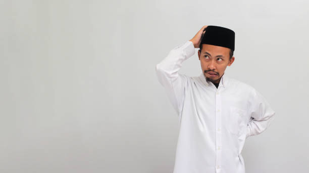 istock Pensive young Indonesian man is scratching his head, deep in thought, isolated on white background 1601919224