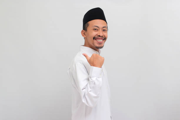 istock Confident young Indonesian man pointing aside at copy space with thumb, isolated on white background 1601925122