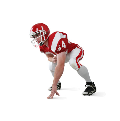 Football player in 3 point stance with determined expression.