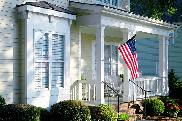 An American Flag hanging from a column on the front porch glows in the morning light as the sun rises.