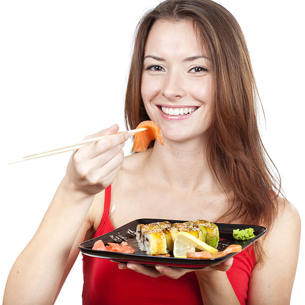 istock beautiful brunette woman eating sushi 160195767