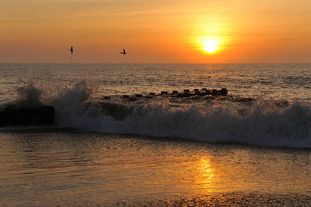 Waves and Beaches are golden while glistening and glowing beneath a summer seashore sunrise.