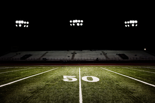 American football field at night under the stadium lights.